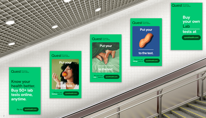 A series of Quest posters in a subway station with the phrase "Put your ___ to the test." Each poster features different imagery, including a peanut, a person eating, and a hand gripping an object, with a consistent green branding.