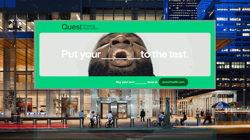 A large Quest billboard ad featuring a close-up of a man yawning, with the phrase "Put your ___ to the test." The advertisement has a bold green and white color scheme.